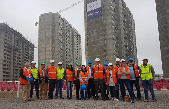 Mission delegates stand in front of apartment blocks in the athletes village 