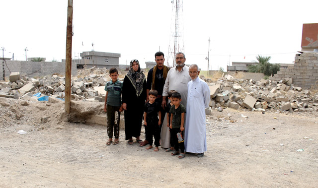 En Irak, une famille pose devant des maisons détruites par les bombardements.
