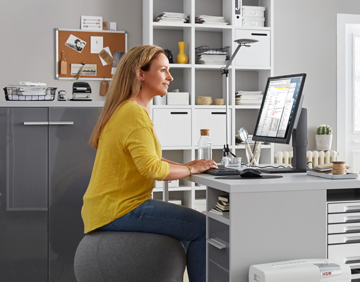 Mitarbeiterin im Homeoffice auf Hocker am Schreibtisch