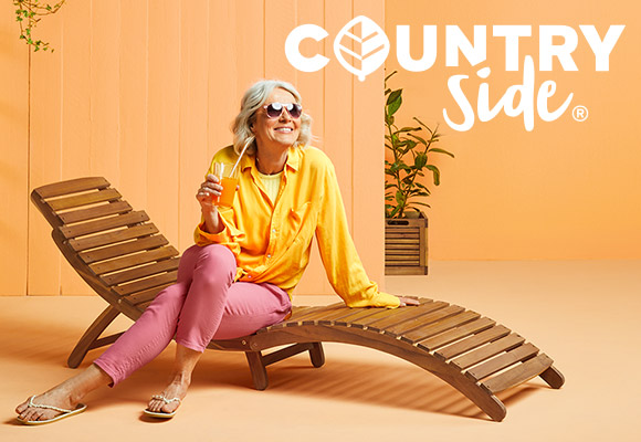 Logo: COUNTRYSIDE®; Abbildung: Frau sitzt auf einer Klapp-Sonnenliege mit einem Getränk in der Hand