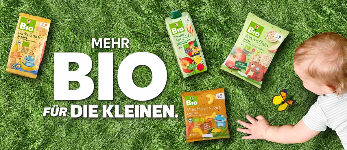 Schriftzug: MEHR BIO FÜR DIE KLEINEN.; Abbildung: Kind; Produktabbildungen: K-BIO Dinkelkekse, K-BIO Milde Säfte, K-BIO Mini-Reiswaffeln, K-BIO Mais-Hirse-Snack