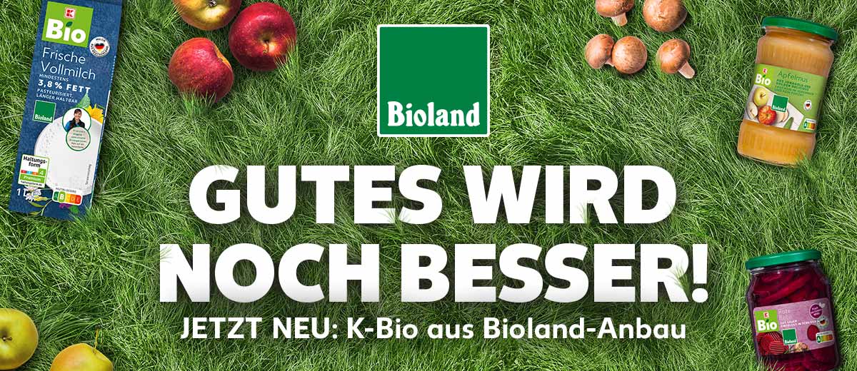 Logo: Bioland; Schriftzug: GUTES WIRD NOCH BESSER! JETZT NEU: K-Bio aus Bioland-Anbau; Hintergrund: Gras; Abbildung: Äpfel und Pilze; Produktabbildungen: K-BIO Bioland Apfelmus, K-BIO Frische Vollmilch 3,5 % Fett