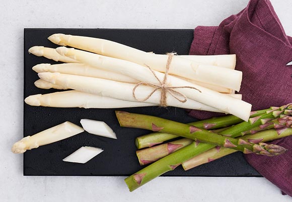 Weißer und grüner Spargel auf einem schwarzen Brett