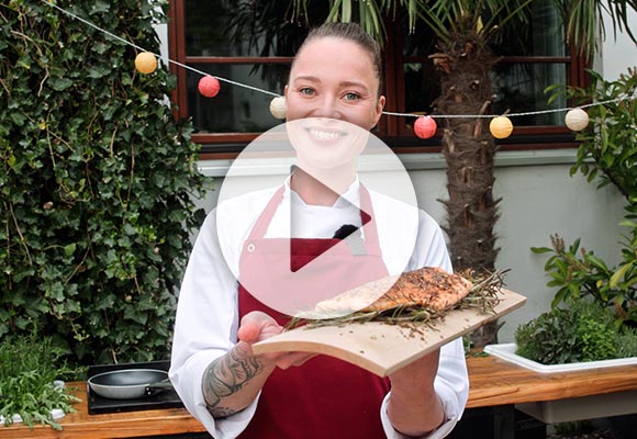 Abbildung: Köchin Verena Leister mit gegrilltem Lachs; Play-Button