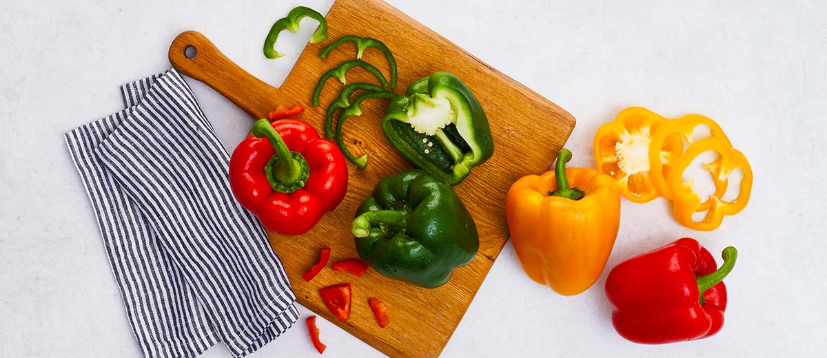 Rote, gelbe und grüne Paprika auf einem Holzbrett