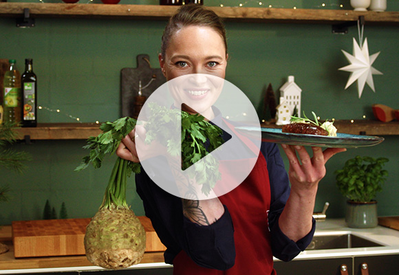 Abbildung: Verena Leister hält eine Knollensellerie in der einen und einen Teller mit veganem Sellerie-„Entenbrust“ mit Kartoffelstampf in der anderen Hand; Abbildung: Play-Button