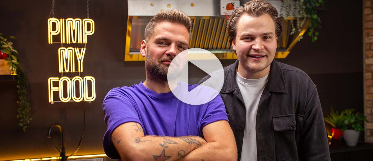 Abbildung: Foodie Niklas und Koch Andy stehen in der Pimp my Food Küche; Abbildung: Play-Button