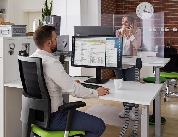 Zwei Personen im BÃ¼ro, am Schreibtisch mit transparenter Tischtrennwand