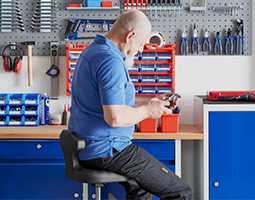 Handwerker an Werkbank mit Werkzeug in der Hand